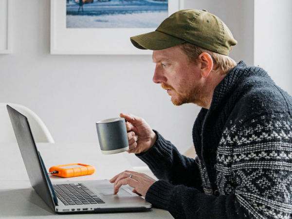 一个人在检查笔记本电脑时喝咖啡